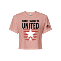 Stuntwomen United light pink women’s cropped T-shirt shown from the front, featuring bold STUNTWOMEN UNITED text with distressed red stripe star graphic and Stunt Team sleeve logo.
