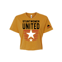 Stuntwomen United mustard yellow women’s cropped T-shirt shown from the front, featuring bold STUNTWOMEN UNITED text with distressed red stripe star graphic and Stunt Team sleeve logo.