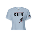 Stuntwomen United light blue women’s cropped T-shirt shown from the front, featuring S.U.N. logo with rappelling stuntwoman graphic in red heels and Stunt Team sleeve logo.