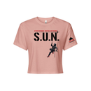 Stuntwomen United light pink women’s cropped T-shirt shown from the front, featuring S.U.N. logo with rappelling stuntwoman graphic in red heels and Stunt Team sleeve logo.