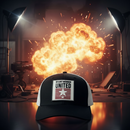 Black and white Stuntwomen United Network Richardson trucker hat with interchangeable rubber patch, photographed on a film set with a staged explosion in the background.