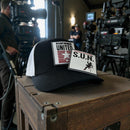 Stuntwomen United Network Richardson trucker hat with interchangeable rubber patch displayed on film equipment during a behind-the-scenes set environment.